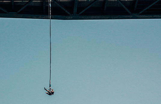 Persona sospesa all'elastico del bungee jumping sotto un ponte